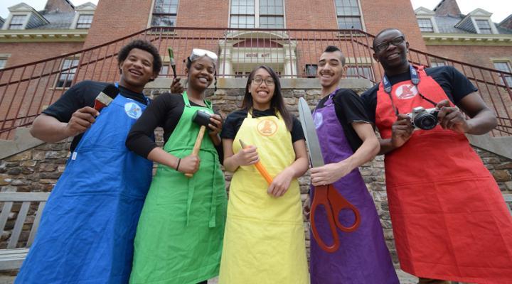 艺术部队五名俱乐部成员穿着彩色围裙和工艺工具摆姿势对着相机